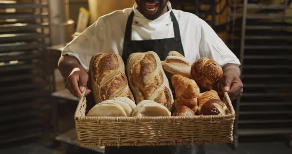 Animation of happy african american male baker holding basket with diverse breads