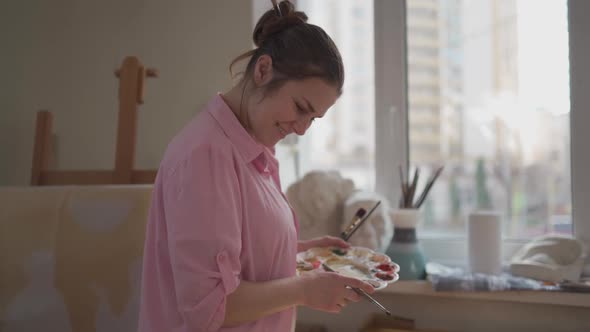 Cute Woman Paints on Canvas in an Art Workshop