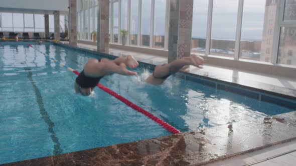 Slowmo of Two Professional Swimmers Diving into Pool