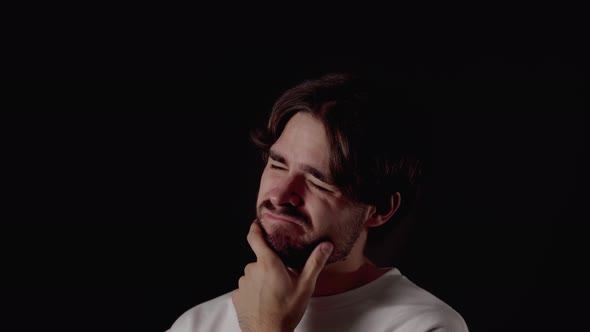 Trendy Young Man thinking and rubbing chin, close, black background