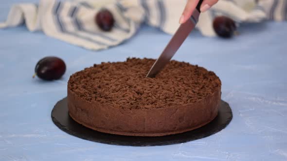 Cutting homemade shortbread chocolate cake with plums.