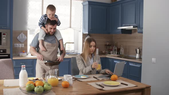 Happy Stay-at-Home Dad Making Breakfast for Busy Wife