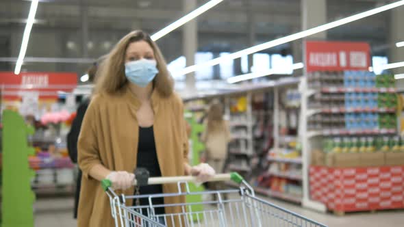Girl in Protective Mask Rubber Gloves Walks in Supermarket with Trolley