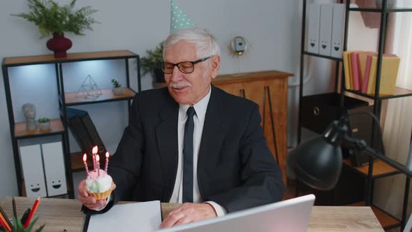 Senior Old Business Man Celebrating Birthday in Office Holding Small Cake with Candles Making a Wish