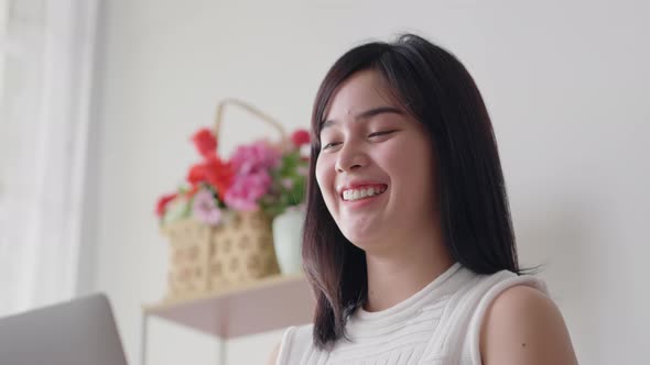 Asian businesswoman happy smiling and typing on laptop keyboard for work from home