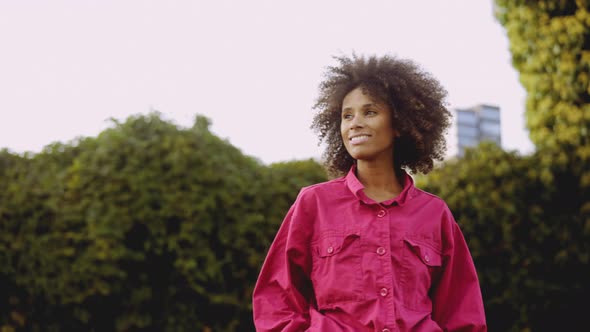 Smiling Young Woman With Afro Hair In Bright Pink Fashion