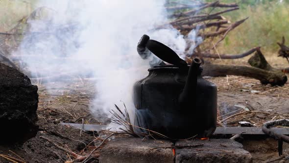 Blackened with Soot Kettle Is Boiling Over an Open Fire on a Tourist Bonfire