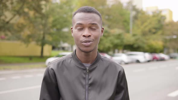 A Young Black Man Talks To the Camera, Puts on a Face Mask and Continues Talking in a Street