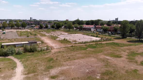 drone aerial view of a undeveloped wasteland full of weeds and grass, along side of a dutch city nei