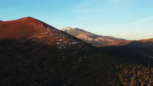 Aerial shot of dawn light illuminating Sunset Crater and the San Francisco Peaks, northeast of Flags