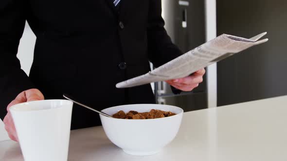 Businessman reading newspaper while having coffee in kitchen