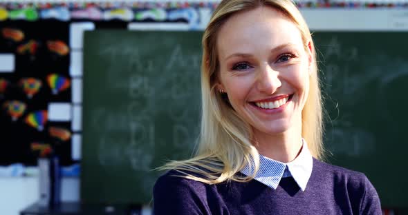 Portrait of happy teacher standing in classroom