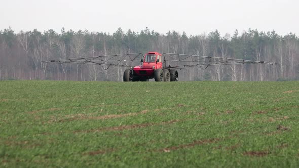Farmer on a Self-propelled Sprayer Processes Rising Winter Crops in Farmland