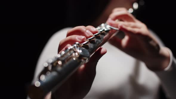 Young Female Musician Plays Music on Flute in Studio Closeup of Fingers