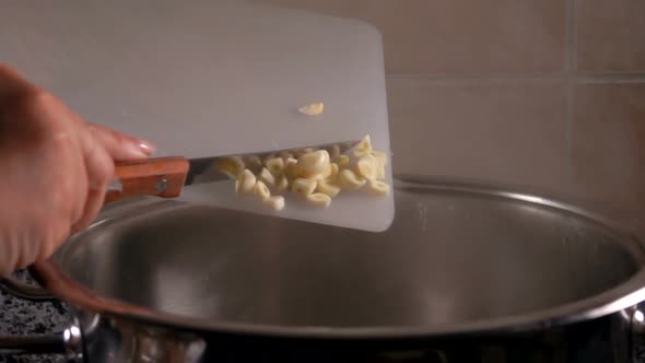 Hostess Pours Finely Chopped Garlic Into the Water