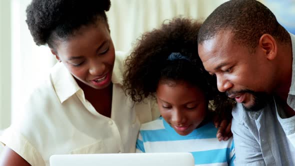 Parents and daughter using laptop in living room