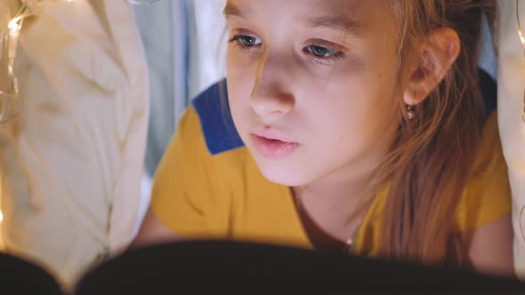 Family Bedtime Pretty Girl Reading Book in a Tent House at Night