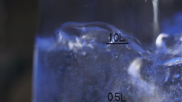 Close Up Footage of Water Boiling in Pot. We See Bubbles of Boiling Water with Mark 1 Liter and Blue