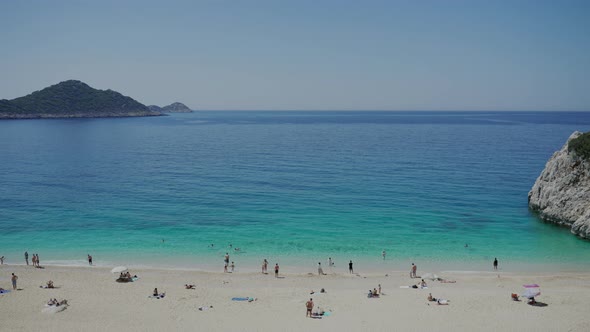 People Enjoy Relaxing on Beach with Soft Sand on Sunny Day