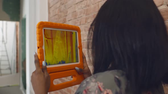 African Woman Detecting Heat Loss in House Using Thermal Viewer on Tablet