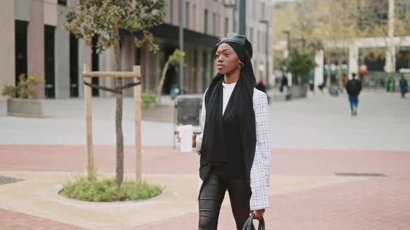 Muslim Woman with Coffee to Go Walking on Street