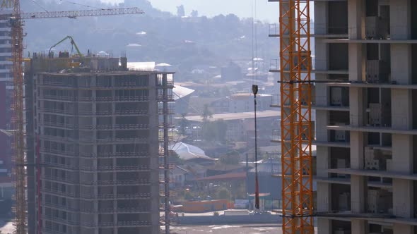 Tower Crane on a Construction Site Lifts a Load at High-rise Building.