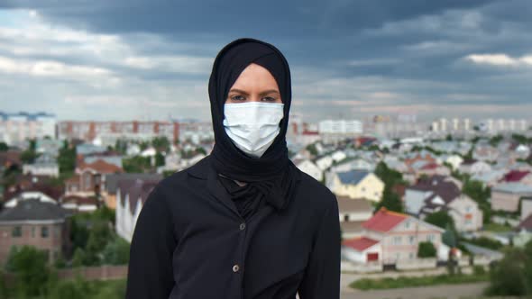 Portrait Muslim Woman in Black Hijab Wearing Protective Medical Face Mask Posing Over Islamic City