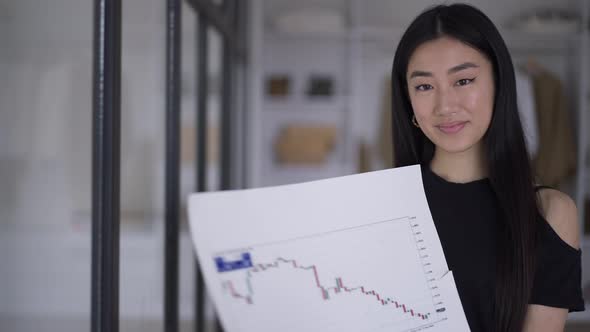 Asian Young Woman Pointing at Business Graph Looking at Camera