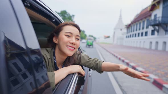 Asian beautiful woman traveler open car window to face air outside.