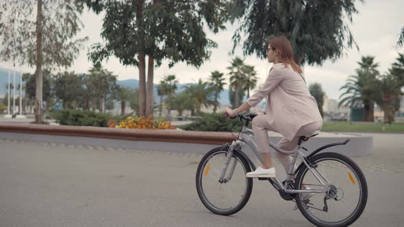 Female City Dweller Is Driving a Bike in Summer Day in Tropical City