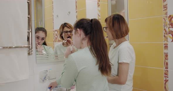 Mom and Daughter Brushing Teeth Together in the Bathroom.