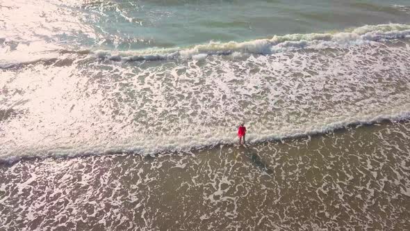 shooting from a drone, a woman enters the sea, and rejoices. happiness.