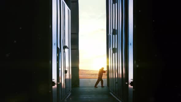 Worker opening Metal Door of a Container Depot at Sunset.