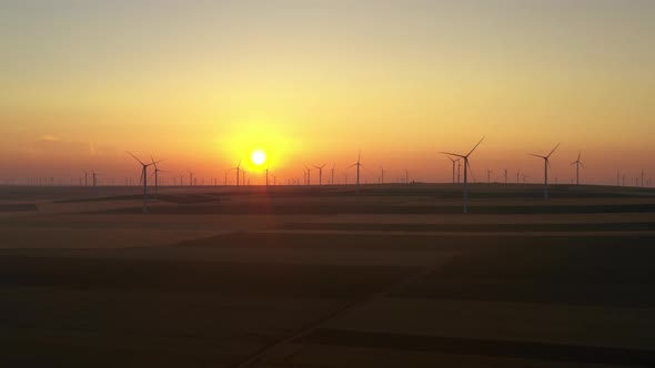 Eolian turbine farm at sunrise. Wind turbine silhouette. Wind field turbines