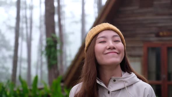 Slow motion of a young woman standing in front of a log cabin in the woods