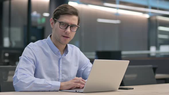 Thumbs Down By Young Man with Laptop at Work