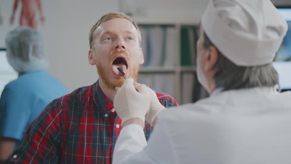 Otolaryngologist Examining Patient Throat with Swollen Glands