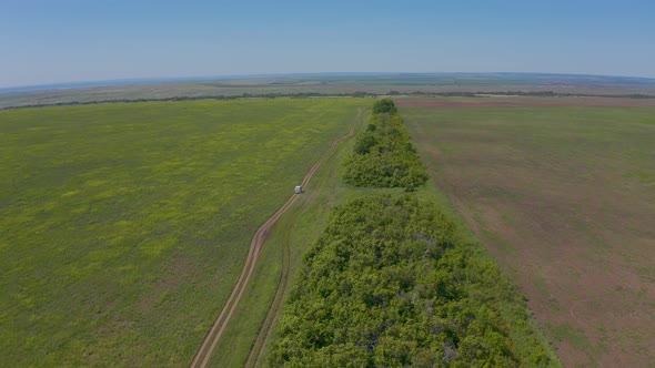 The Minibus Drives Through the Green Field Next to the Boarding Station