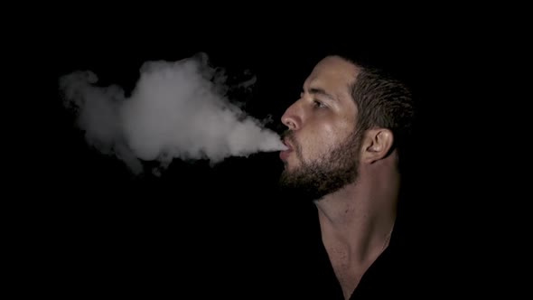 Man smoking electronic cigarette vapor on black background.