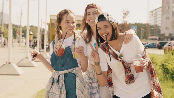 Positive models holding and drinking fresh cocktail smoothie outdoors