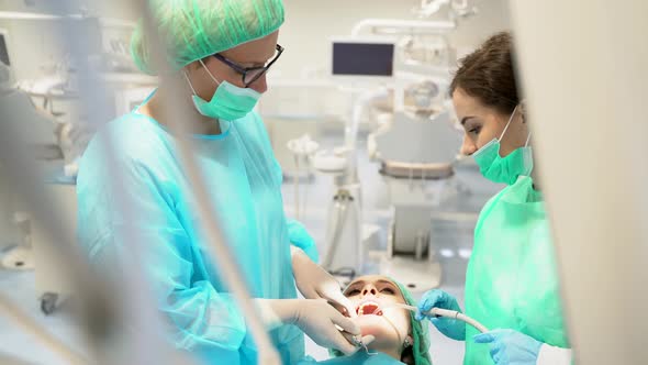 Female dentist and her assistant examining the teeth of a patient