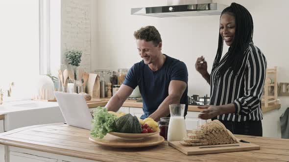 Happy married interracial couple talking in kitchen at home in the morning