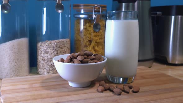 Slider Shot of a Glass of Almond Milk and a Bowl of Almonds on a Kitchen Counter