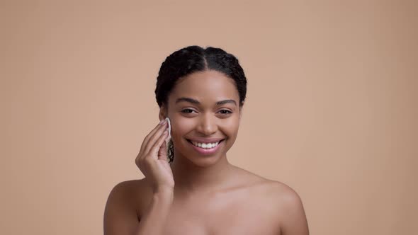 Young Beautiful Wellgroomed Black Woman Cleaning Her Face with Cleansing Lotion and Cotton Pad