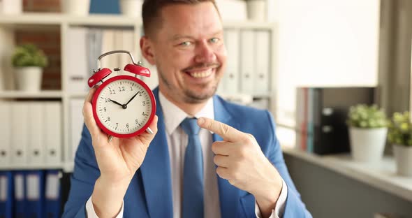 Young Smiling Businessman Showing Time on Alarm Clock with His Forefinger  Movie