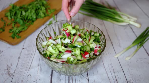 Hands Chef Stirring with a Spoon a Vegetable Salad with Radish Cucumber Greens