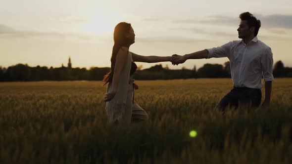 Slow motion shot of couple walking hand in hand on field in theevening
