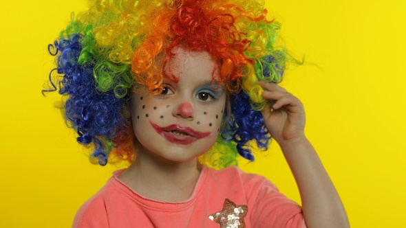 Little Child Girl Clown in Colorful Wig Tells Something Interesting, Having Fun, Smiling. Halloween