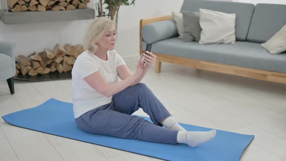 Senior Old Woman Using Smartphone on Yoga Mat at Home