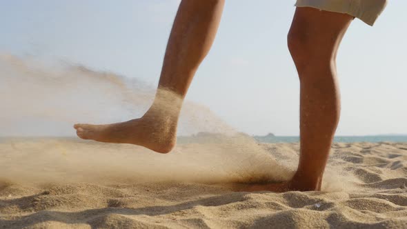 Close up feet of Asian young male playing soccer alone on the beach on holiday vacation.